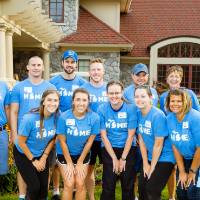 Alumni pose in front of the Alumni House
